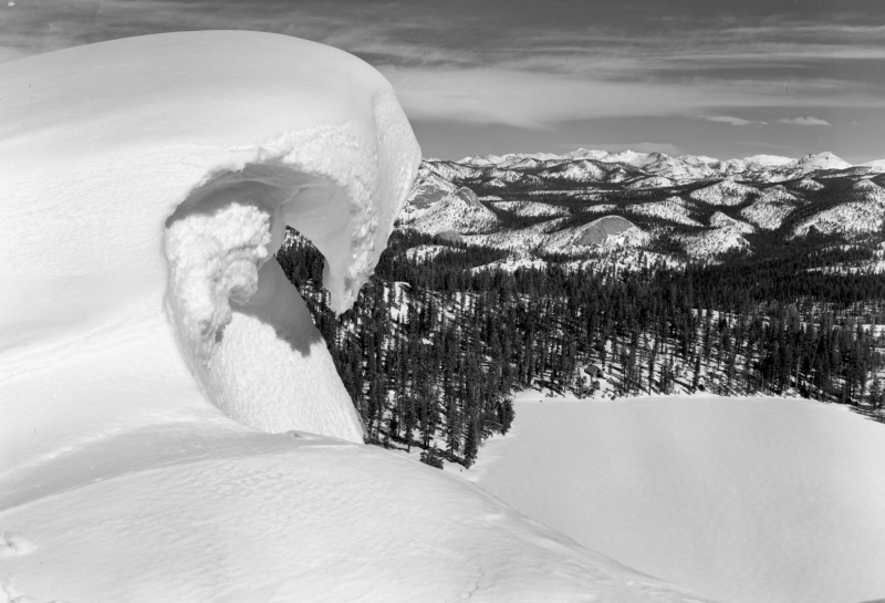Snow cornices form when wind-blown snow builds up sideways and juts out over ridges or summits, creating dangerous unstable ledges. (Undated archival photo, courtesy of NPS)