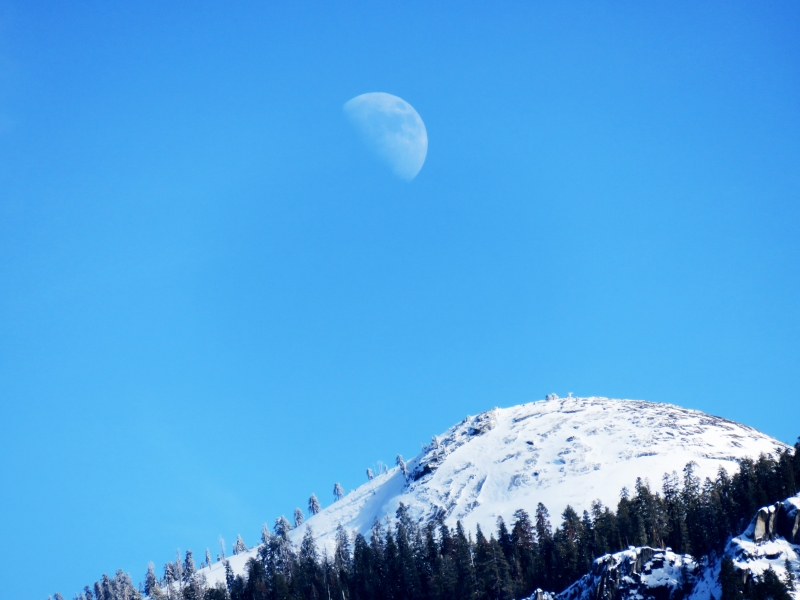 A snow-covered Yosemite dome mirrors the curve of a faint winter moon. Photo: Carolyn Botell.